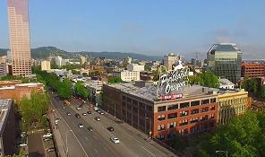 Aerial view of Portland, Oregon, showing downtown buildings, greenery, and highway traffic.